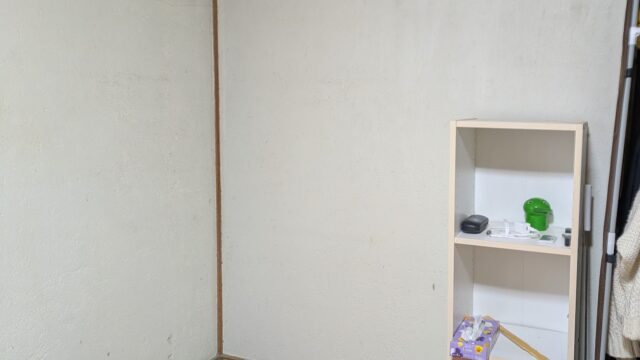 布団の枕元から収納用品３台を撤去し、頭から離れた場所にボックス１台がある寝室の様子